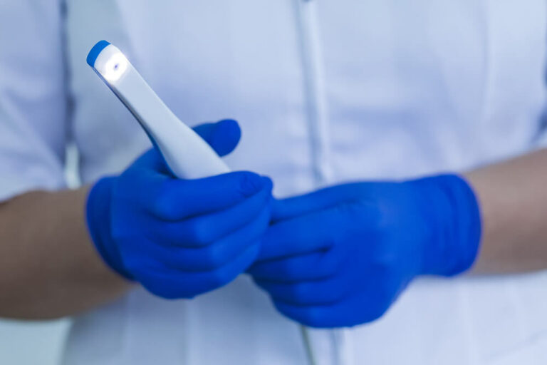 dentist with blue gloves holding a intraoral camera