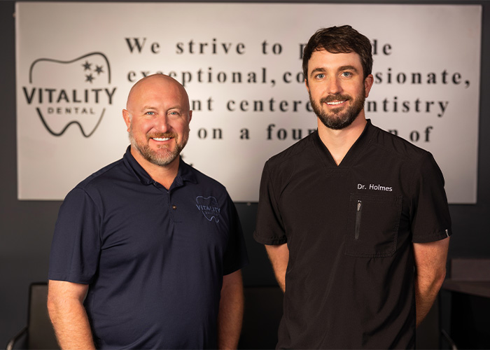 Dr. Oakes and Dr. Holmes standing in front of Vitality Dental's mission statement